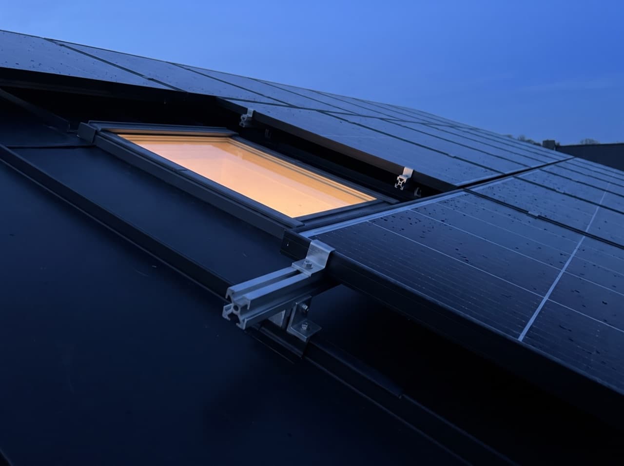 Illustrative image: photovoltaic modules on a dark roof at blue hour